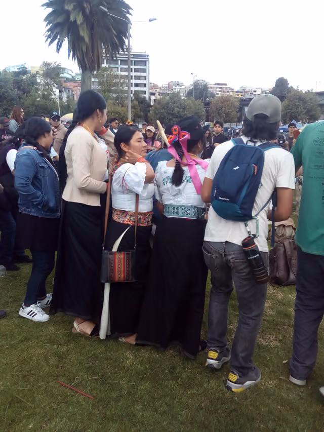 Indigenous people dance in circles in a park in Quito