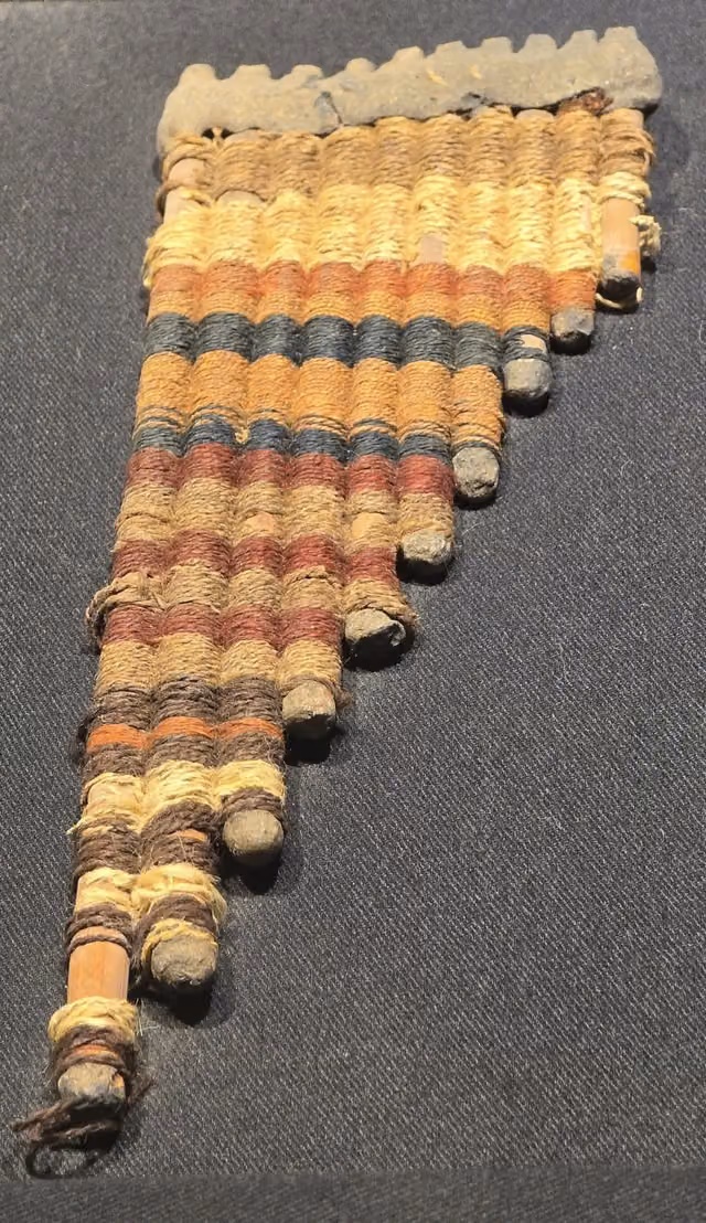 Zampoña de la cultura Nazca (200 a. C.–750 d. C.) con hilos textiles