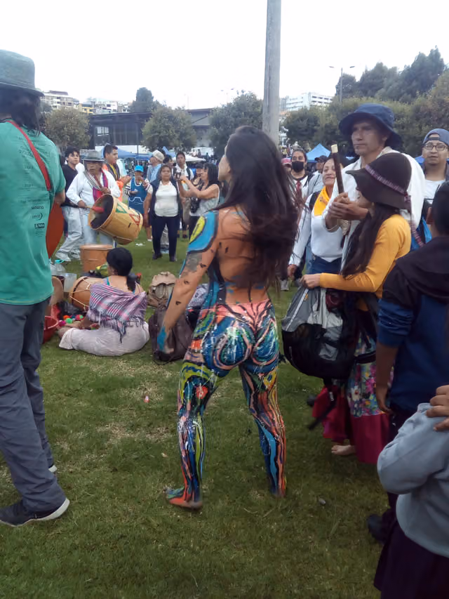 Musicians and dancers dance in circles in a park in Quito