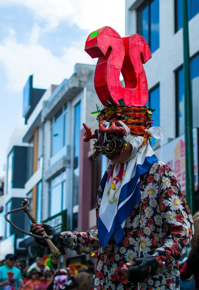 Diablo de la Diablada Pillareña con careta de diseño vertical y traje de flores